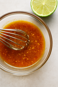 A rich, amber-hued marinade swirled in a ceramic bowl—honey glistens alongside specks of smoky paprika, fresh lime zest, and minced garlic, evoking a bold blend of summer heat and citrusy sweetness.

