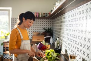 Woman in a kitchen chopping vegetables.